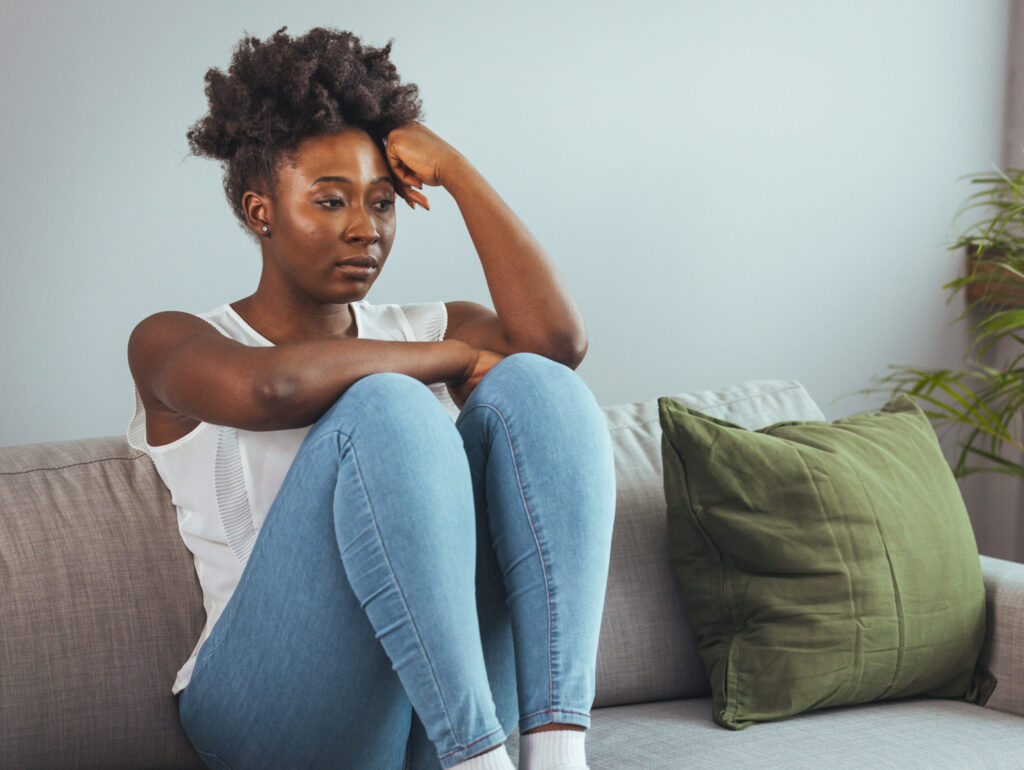 A woman sitting on her couch upset and lonely (Credit: Photo captured by Dragana Gordic via Shutterstock)