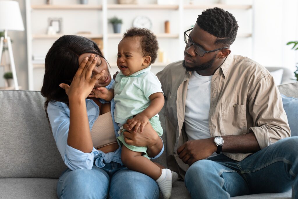 Wife dealing with postpartum depression as her husband comforts her (Credit: Prostock-studio/Shutterstock)