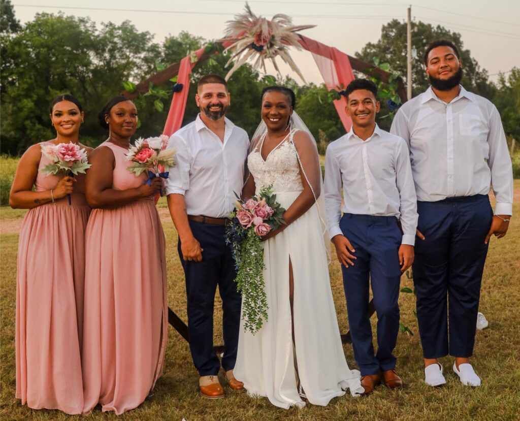 A bride and groom surrounded by their wedding party (Credit: So Her Designs LLC)