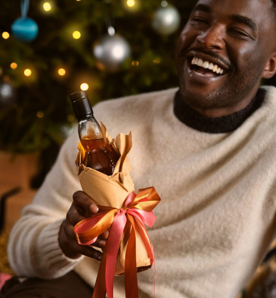 A man holding a gifted bottle of whiskey as part of a roundup of Christmas gifts for men. (Credit: OurWhisky Foundation via Unsplash)