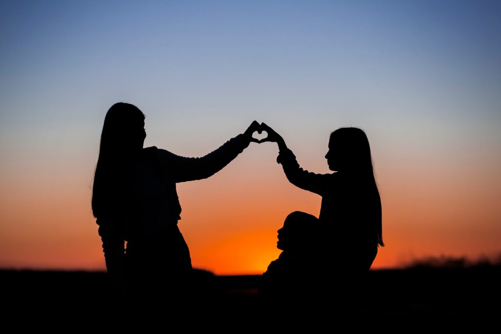 Two sisters making a heart sign as part of a maintaining relationships in today's day and age.(Credit: u_uf78c121 via Pixabay)