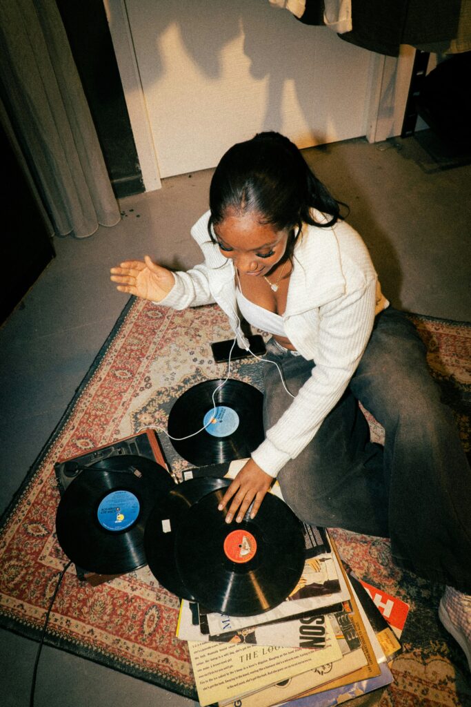 Woman using a vinyl record player as part of a story on 10 essentials for your return to analog. (Credit: Christian Agbede via Unsplash)