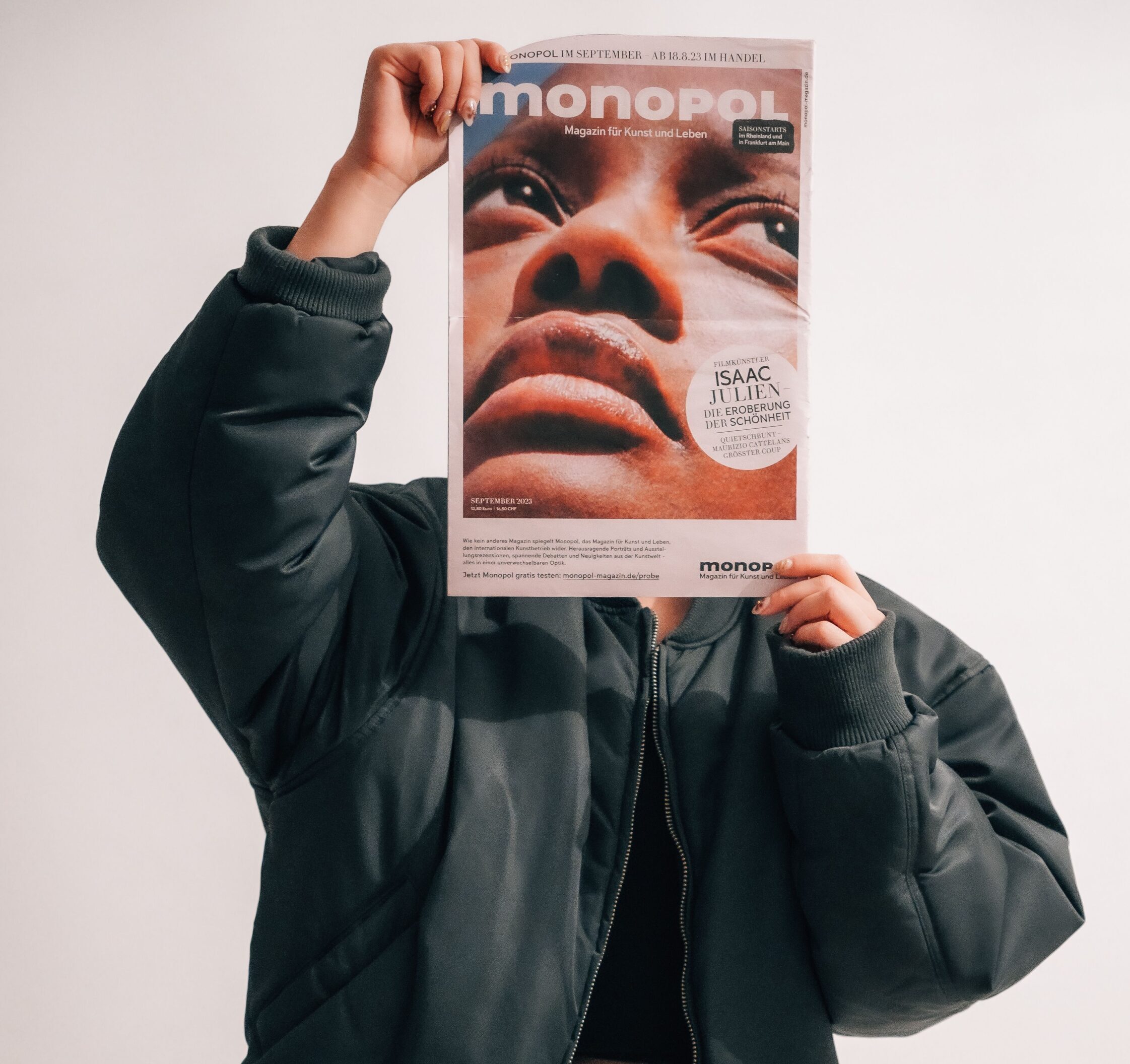 A woman holding a magazine up to her face. (Credit: Shuttercraftsman via Pexels)
